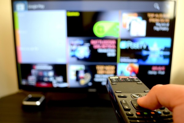 Photograph of a person cycling through their smart tv with the remote.