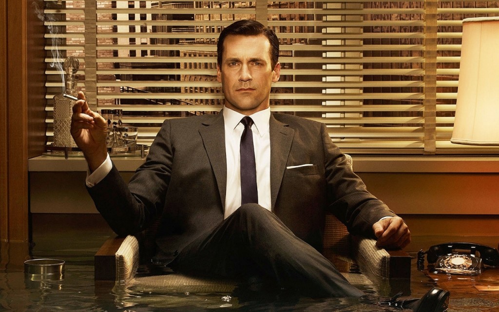 Don Draper sitting in his office, holding a cigarette, staring into the camera.