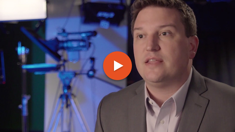 Thumbnail of a man wearing a blazer and button down shirt interviewing in a video production room.