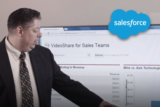 Man in office pointing to screen displaying Video Share for sales teams. Blue cloud Salesforce logo in top right corner.