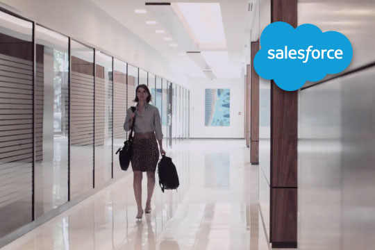 Screenshot of a woman carrying a satchel down a hallway with the salesforce logo overlaying the image.