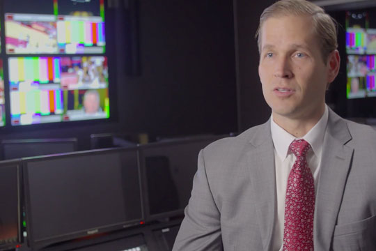 Profile image of a man wearing a suit in a video production studio.