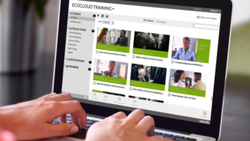 Hands typing on a laptop, screen shows EcoCloud training using uStudio video content management.