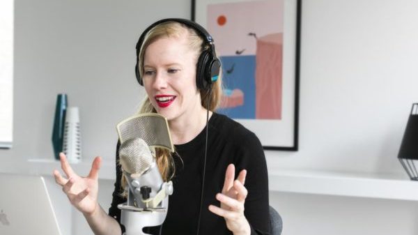 woman speaking into a microphone to produce a private podcast